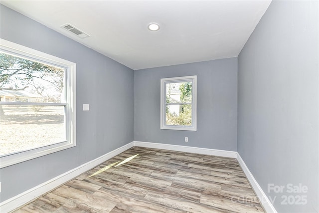 unfurnished room featuring wood finished floors, visible vents, and baseboards