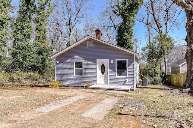 bungalow featuring central AC unit, a chimney, and fence