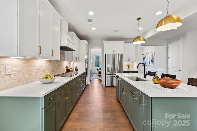 kitchen with decorative light fixtures, light countertops, appliances with stainless steel finishes, white cabinets, and a sink