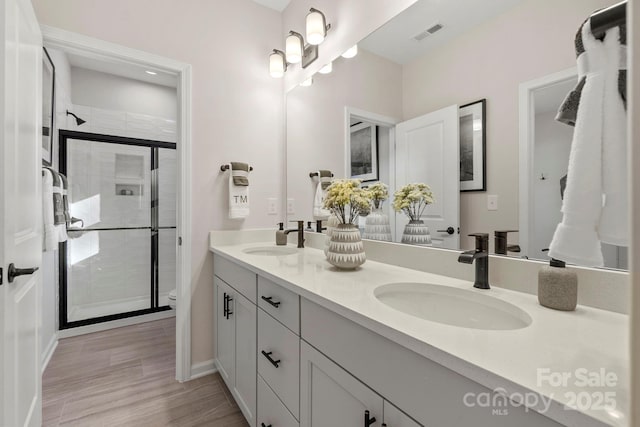 bathroom featuring toilet, a stall shower, visible vents, and a sink