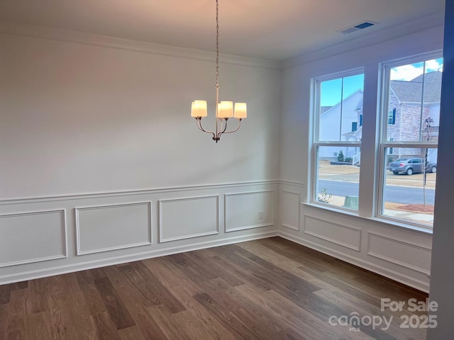 unfurnished dining area featuring dark wood-style floors, visible vents, a notable chandelier, and crown molding