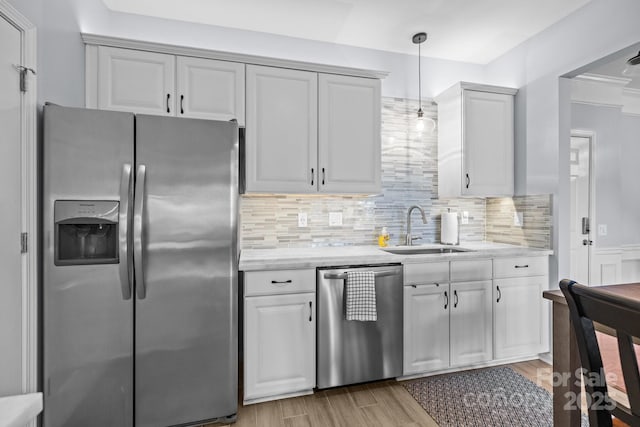 kitchen featuring a sink, white cabinets, light wood-style floors, appliances with stainless steel finishes, and tasteful backsplash