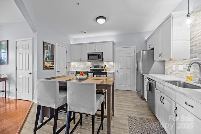 kitchen featuring tasteful backsplash, visible vents, appliances with stainless steel finishes, light wood-style floors, and a sink