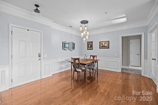 dining area with a chandelier, a decorative wall, and wood finished floors