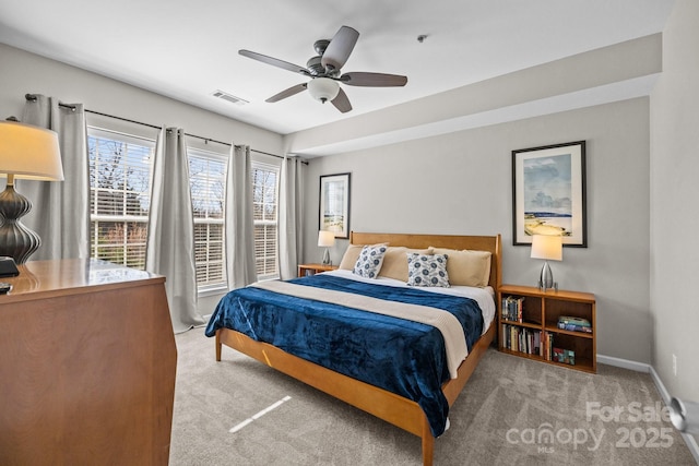 carpeted bedroom featuring a ceiling fan, visible vents, and baseboards