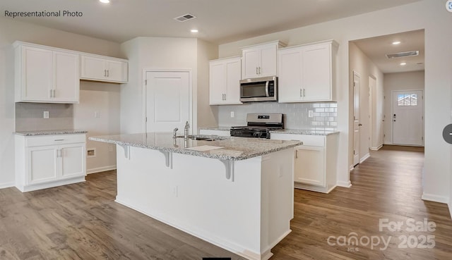 kitchen with white cabinetry, a center island with sink, visible vents, and stainless steel appliances