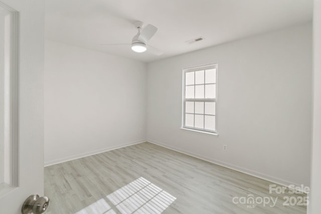 spare room with visible vents, ceiling fan, light wood-style flooring, and baseboards