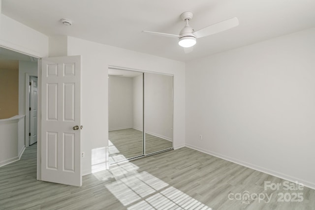 unfurnished bedroom featuring ceiling fan, a closet, light wood-style flooring, and baseboards