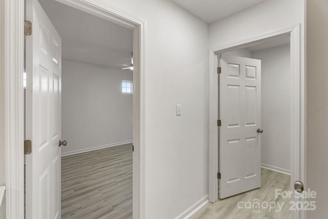 corridor with light wood-type flooring and baseboards