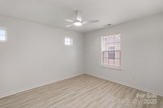 spare room with light wood-style floors, baseboards, visible vents, and a ceiling fan