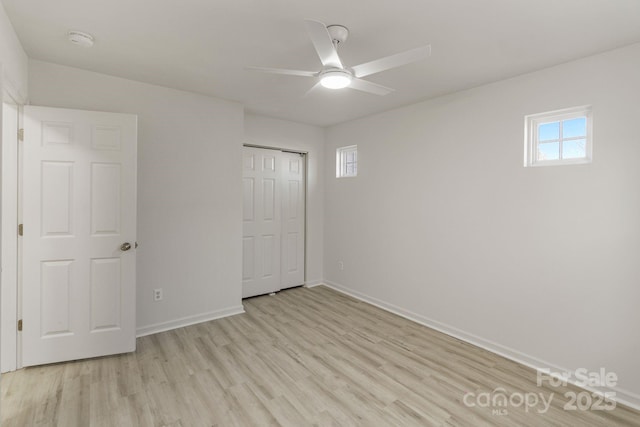 unfurnished bedroom featuring light wood finished floors, a ceiling fan, baseboards, and a closet