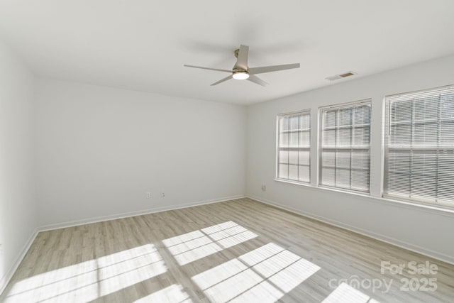 empty room with a ceiling fan, visible vents, light wood-style flooring, and baseboards