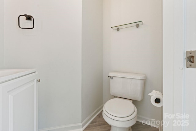 bathroom with toilet, baseboards, wood finished floors, and vanity