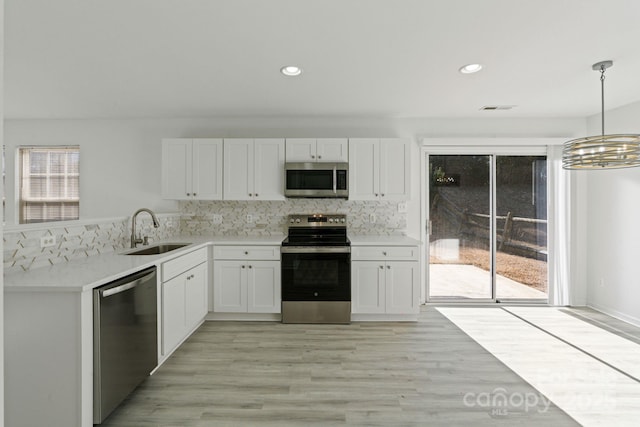 kitchen with stainless steel appliances, a sink, visible vents, white cabinets, and pendant lighting