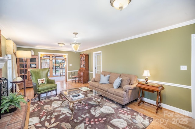 living room featuring a fireplace, crown molding, baseboards, and wood finished floors