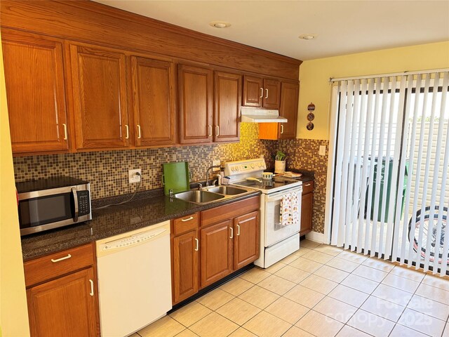 kitchen featuring white appliances, brown cabinets, a sink, and under cabinet range hood