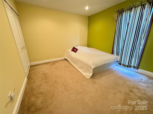 unfurnished bedroom featuring light carpet, baseboards, a closet, and recessed lighting