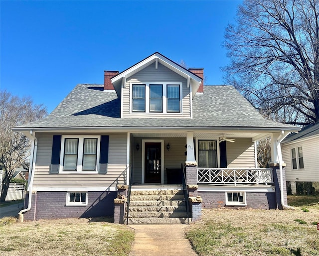 bungalow-style house with a porch, a front yard, roof with shingles, and a chimney