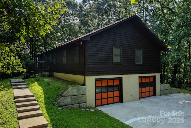 view of side of home with an attached garage, driveway, and stairway