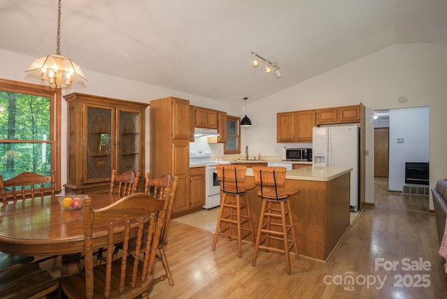 kitchen featuring brown cabinets, white appliances, light countertops, and hanging light fixtures