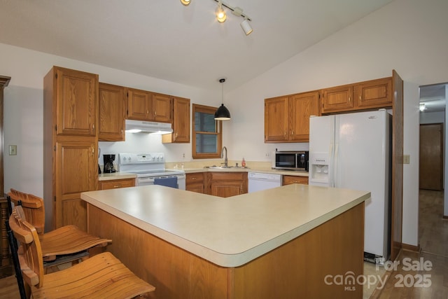 kitchen with white appliances, light countertops, hanging light fixtures, and under cabinet range hood