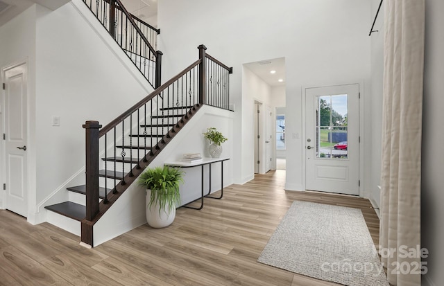 foyer featuring light wood-style floors, baseboards, and a high ceiling