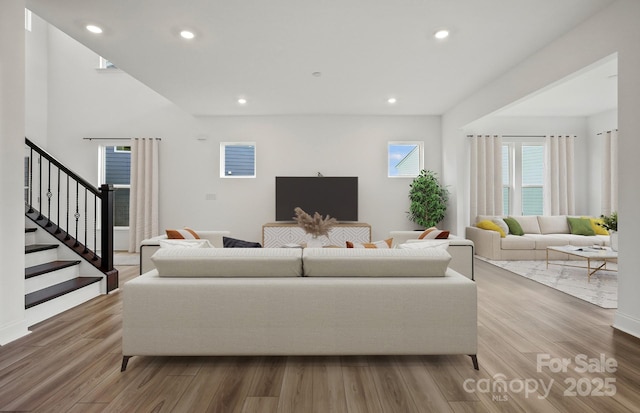 living area with recessed lighting, stairway, and wood finished floors