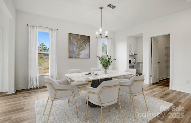 dining space featuring a healthy amount of sunlight, visible vents, and light wood finished floors