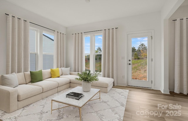 unfurnished living room featuring baseboards, plenty of natural light, and light wood-style floors