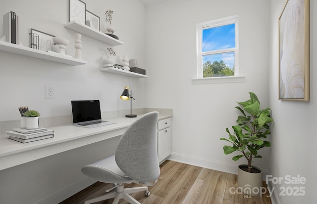 home office featuring light wood finished floors, baseboards, and built in desk