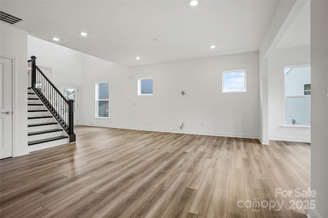 unfurnished living room with recessed lighting, visible vents, light wood-style flooring, baseboards, and stairs