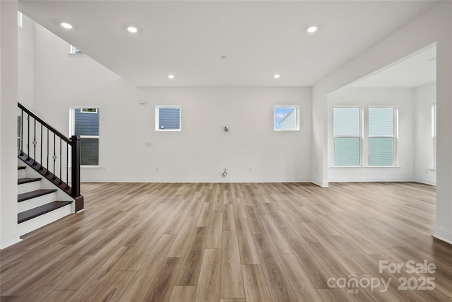 unfurnished living room featuring light wood-style floors, stairs, baseboards, and recessed lighting