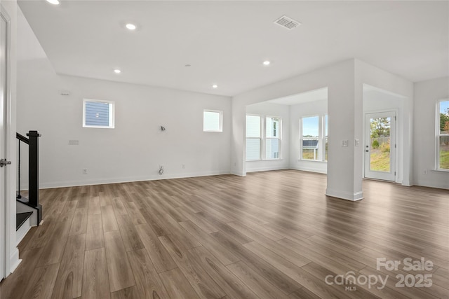 unfurnished living room with light wood-type flooring, plenty of natural light, visible vents, and recessed lighting