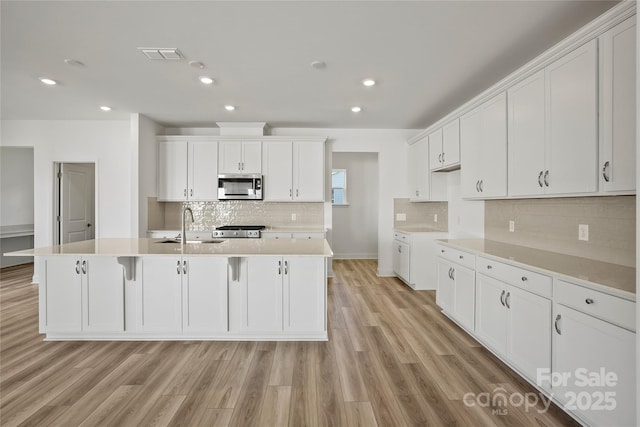 kitchen with light countertops, white cabinets, and stainless steel microwave