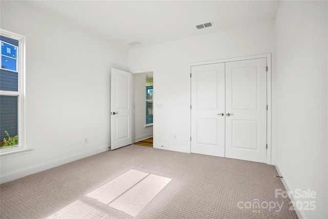 unfurnished bedroom featuring a closet, carpet, visible vents, and baseboards