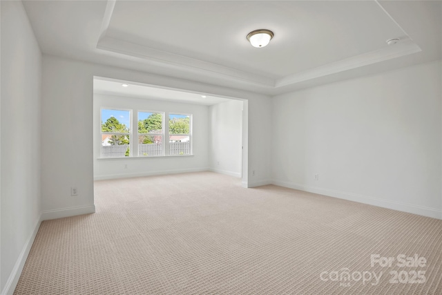 spare room with light carpet, baseboards, and a tray ceiling