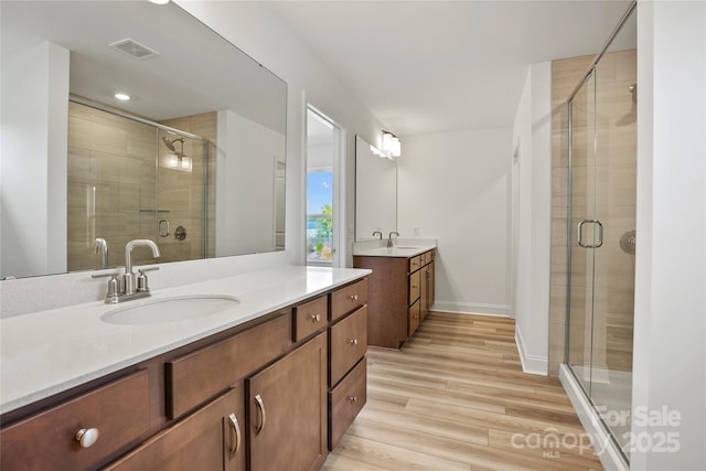 bathroom featuring visible vents, two vanities, a sink, and wood finished floors