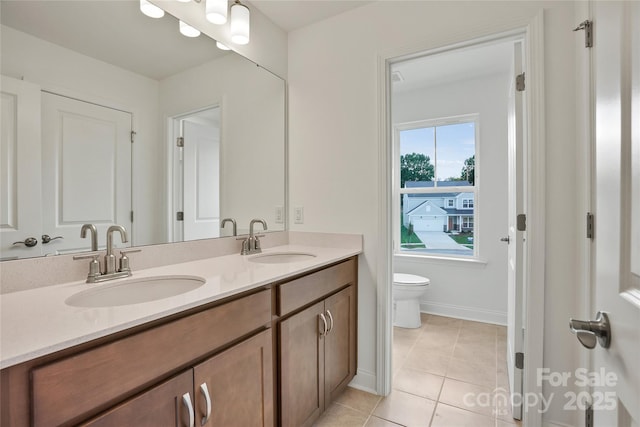 full bath with double vanity, a sink, toilet, and tile patterned floors