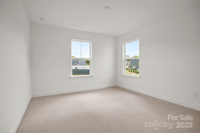 carpeted empty room featuring a healthy amount of sunlight and baseboards