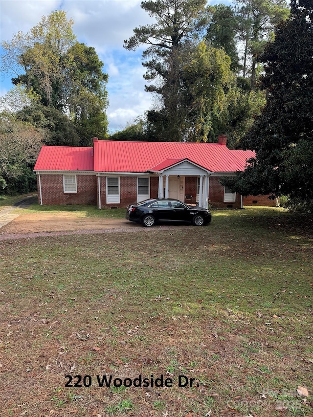 view of front of house featuring a front yard, a chimney, metal roof, and brick siding