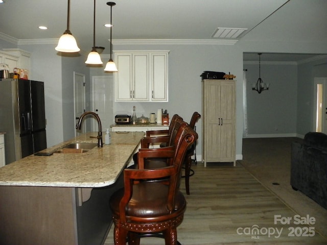 128 Summerlake Dr, New London, NC 28127 - kitchen with an island with sink, decorative light fixtures, black refrigerator with ice dispenser, crown molding, and a sink