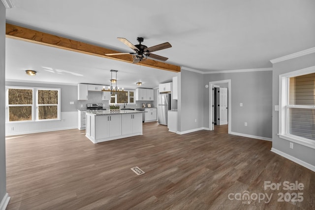 unfurnished living room with baseboards, visible vents, dark wood-type flooring, crown molding, and ceiling fan with notable chandelier