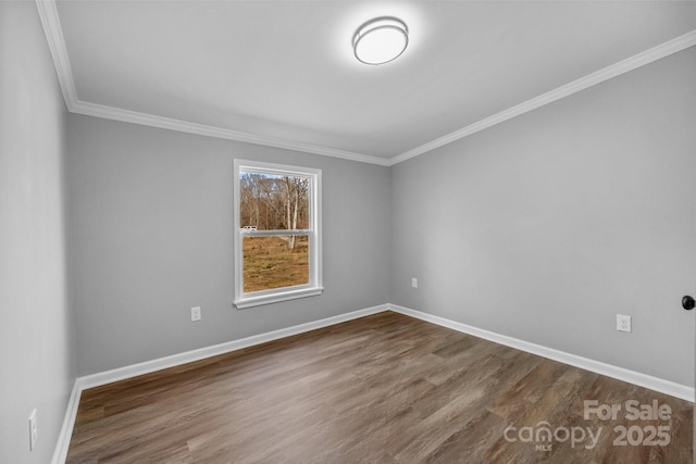 empty room featuring dark wood-style floors, crown molding, and baseboards