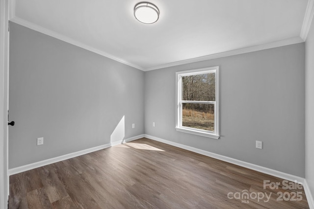 empty room with ornamental molding, wood finished floors, and baseboards