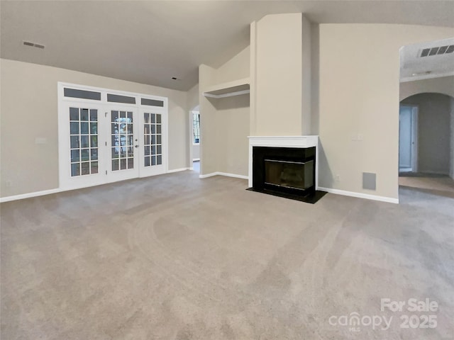 unfurnished living room featuring vaulted ceiling, carpet, a multi sided fireplace, and visible vents