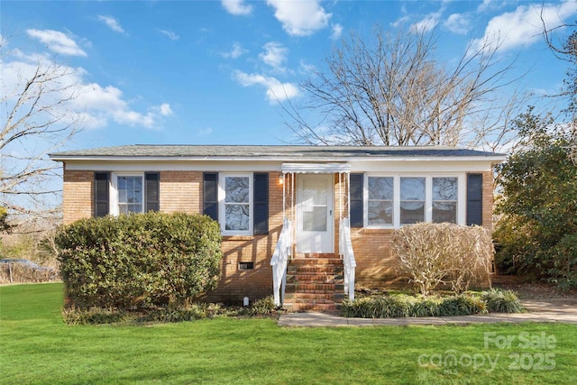 view of front facade featuring entry steps, brick siding, and a front yard