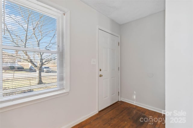 entryway with dark wood-type flooring, a textured ceiling, and baseboards