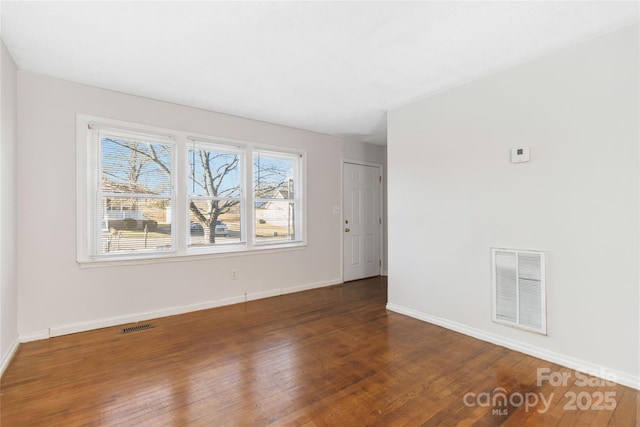 unfurnished room featuring baseboards, visible vents, and dark wood-type flooring