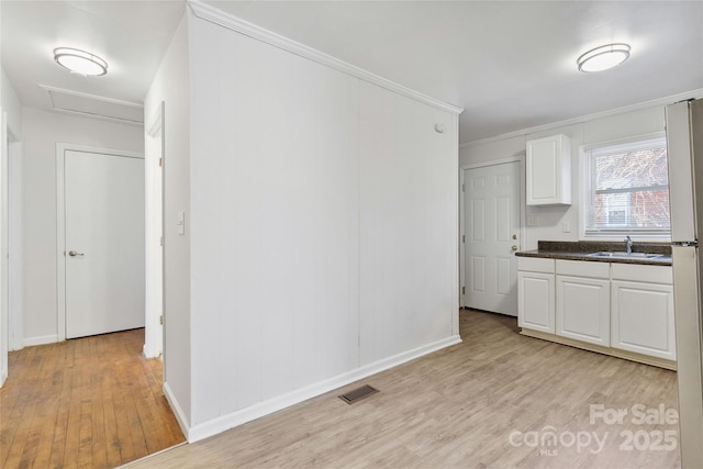 kitchen featuring dark countertops, light wood finished floors, visible vents, and white cabinets