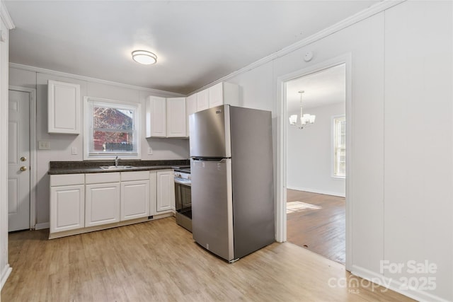 kitchen with light wood-style flooring, a sink, white cabinets, appliances with stainless steel finishes, and dark countertops